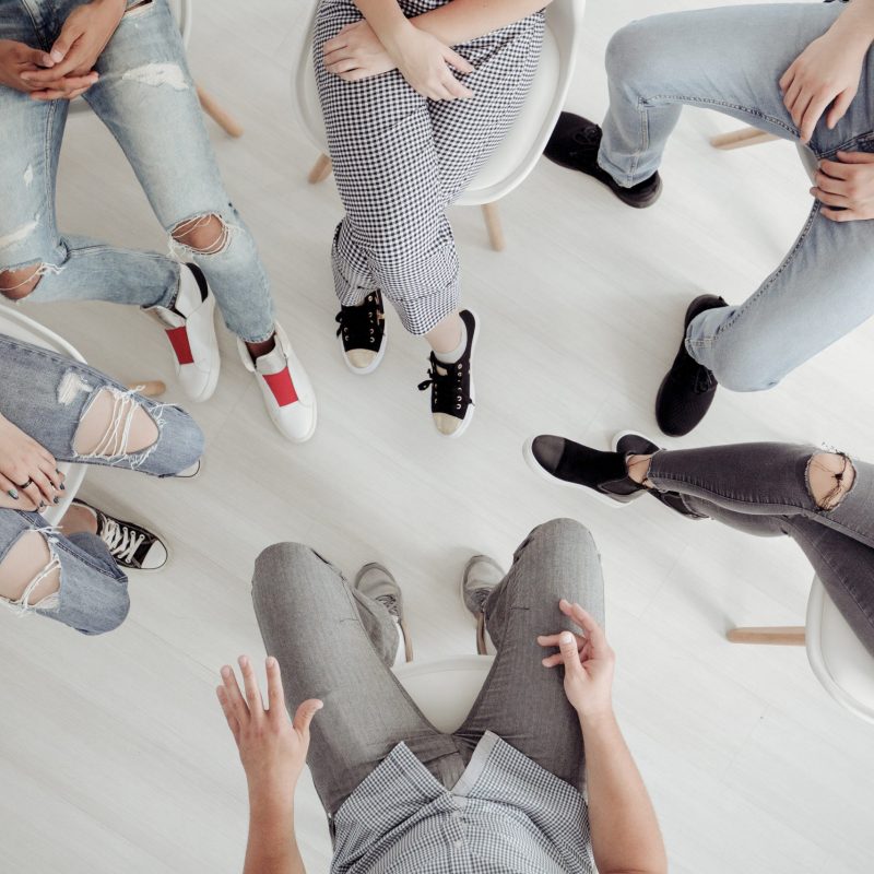 Top view of troublesome teenagers and their therapist during professional talk with counselor